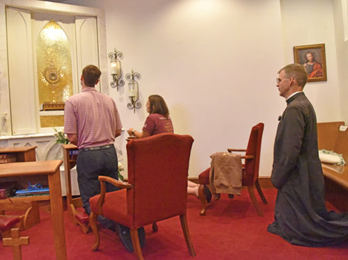 Ethan Green, left, Lucy Merth and Father Jonathan Meyer kneel in prayer before the Blessed Sacrament on July 22 in the perpetual adoration chapel of St. Luke the Evangelist Parish in Indianapolis. The three and another young adult visited all 16 perpetual adoration chapels in the archdiocese that day. (Photo by Sean Gallagher)