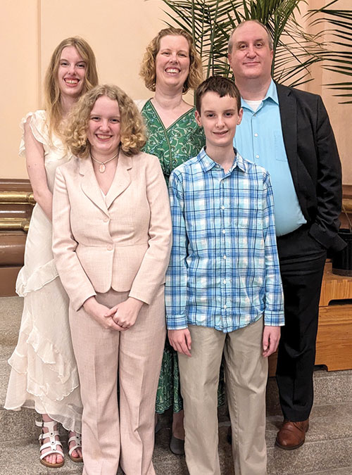 Andrew and Julie Motyka pose for a photo with their children&mdash;front row, Mary and Thomas; back row, Lucy &mdash;at Easter in 2026. When their children were infants, Andrew hummed the lyrics to &ldquo;God with Hidden Majesty&rdquo; to them. (Submitted photo)