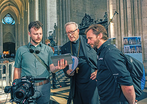 Branden Stanley, left, works with Bishop Robert E. Barron of Winona-Rochester in Minnesota, and Devin Dailey, who works for Word on Fire, a ministry founded by Bishop Barron, on July 15, 2025, in Notre Dame Cathedral in Rheims, France. Stanley, who grew up in the Archdiocese of Indianapolis, is a co-director of Heaven in Stone and Glass, a documentary narrated by Bishop Barron about Gothic churches in France. (Photo courtesy of Spirit Juice Studios)