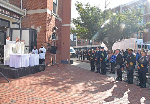 With members of the Indianapolis Fire Department (IFD), their families and civic leaders looking on, Deacon Gary Blackwell, left, and Father John McCaslin elevate the Eucharist during a Mass celebrated on Sept. 11 outside the Indianapolis Firefighters Museum in Indianapolis as part of IFD’s observance of the 25th anniversary of the 9/11 terrorist attacks. (Photos by Sean Gallagher)