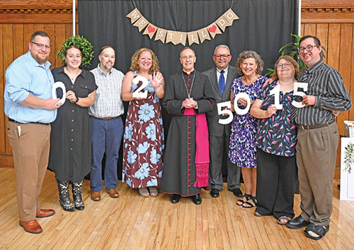 Larry and Andrea Fleck, fourth and third from right, celebrating their 50th anniversary this year, pose with Archbishop Charles C. Thompson and other members of their family at a reception in the Archbishop Edward T. O&rsquo;Meara Catholic Center in Indianapolis on Aug. 30 following the annual archdiocesan Wedding Anniversary Mass across the street in SS. Peter and Paul Cathedral. Second from left is the couple&rsquo;s granddaughter, Jacqueline Hughey, who is engaged to Patrick Sauers, left. To her right are her parents David and Dora Hughey&mdash;the Flecks&rsquo; daughter&mdash;marking their 25th year of marriage. To Andrea&rsquo;s right are Mandy and Nathan Fleck&mdash;the couple&rsquo;s son&mdash;who have been married 15 years. (Photo by Natalie Hoefer)