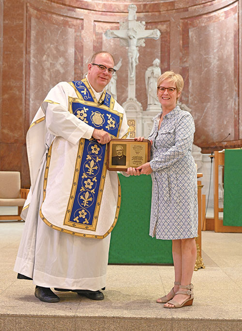 Sheryl Dye receives this year&rsquo;s archdiocesan Archbishop Edward T. O&rsquo;Meara Respect Life Award from Father C. Ryan McCarthy, spiritual director for Bishop Simon Brut&eacute; College Seminary in Indianapolis, at the end of a Mass at SS. Peter and Paul Cathedral in Indianapolis on Oct. 4, Respect Life Sunday. (Photo by Natalie Hoefer)